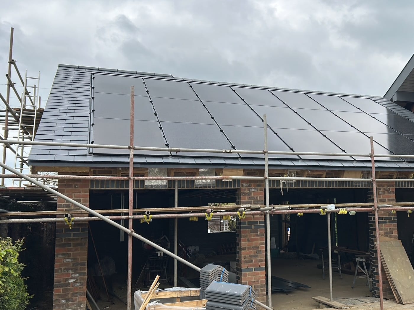 Full-width solar array on a slate roof, scaffolding still up during an Athena install