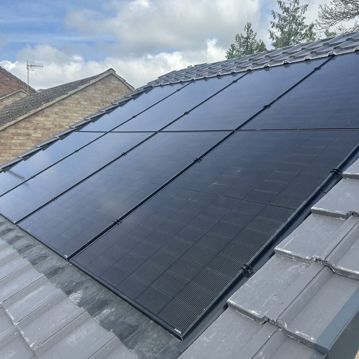 Close-up of all-black solar panels set into a grey tiled roof