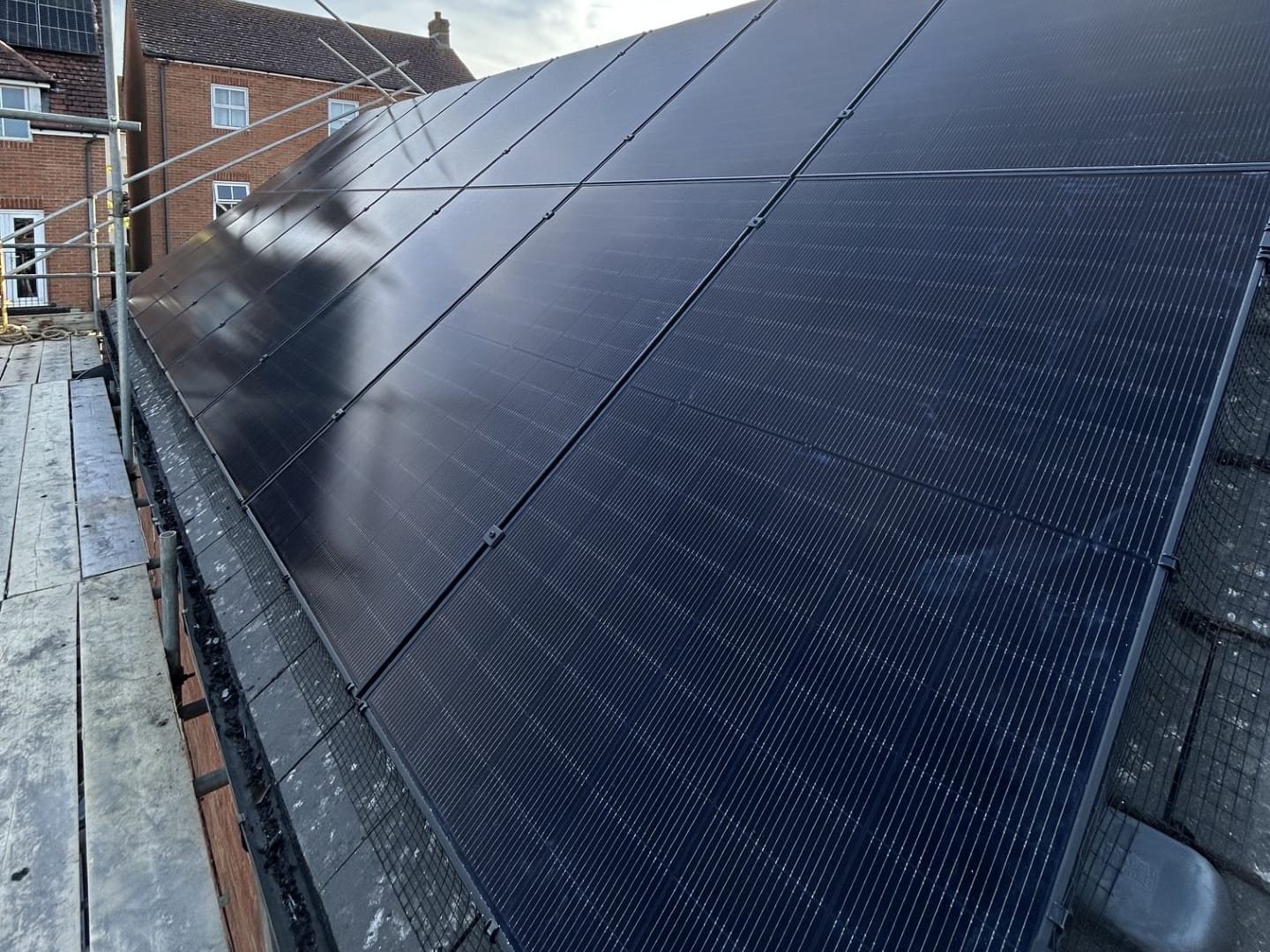 All-black solar panels on a slate roof, seen from the scaffold during an Athena install